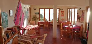 una sala da pranzo con tavoli, sedie e finestre di Hostal Inti Wayra a Comunidad Yumani