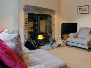 uma sala de estar com uma lareira com um sofá e uma lareira em Middlegate Cottage em Hawes