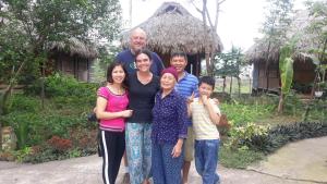 una famiglia che posa per una foto davanti a una casa di Cuc Phuong Bungalow a Nho Quan