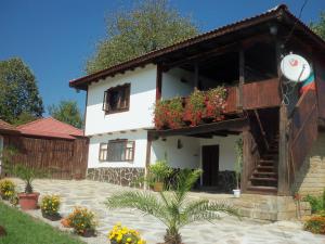 uma casa branca com flores à frente em Митровата къща em Raynovtsi