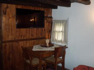 a dining room with a table with chairs and a television at Митровата къща in Raynovtsi