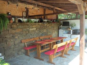 a wooden table and benches in a kitchen with a stone wall at Митровата къща in Raynovtsi