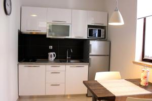 a kitchen with white cabinets and a stainless steel refrigerator at Alison Apartments in Premantura