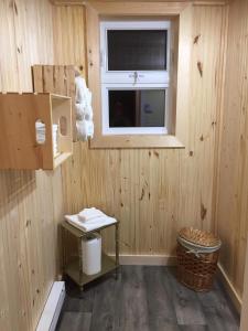 a wooden room with a window and a trash can at La petite maison sur la côte in Sainte-Anne-des-Monts +16 photos