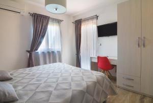 a bedroom with a bed and a desk and a window at Alison Apartments in Premantura