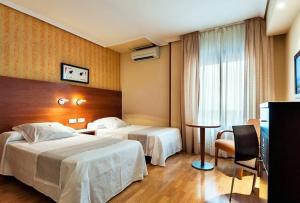ein Hotelzimmer mit 2 Betten und einem Fenster in der Unterkunft Hotel Xauen in Jaén
