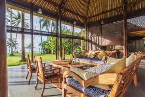 a living room with a table and chairs and windows at Citakara Sari Villas in Candidasa