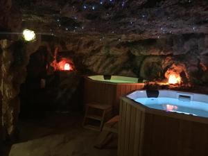 a cave with two hot tubs and a fireplace at Gorgeous Villa in Cluj-Napoca