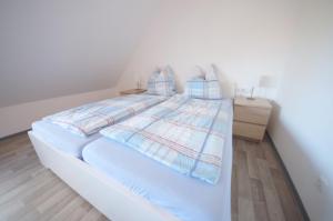 ein Schlafzimmer mit einem weißen Bett mit Kissen in der Unterkunft Appartementhaus Nige Ooge Ferienwohnung Nr. 12 in Cuxhaven
