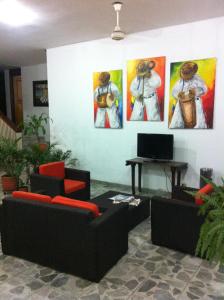 Habitación con 2 sofás y pinturas en la pared. en Hotel Betoma, en Santa Marta