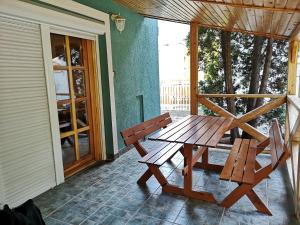 a wooden picnic table and two chairs on a porch at Azúr Vendégház in Hajdúszoboszló
