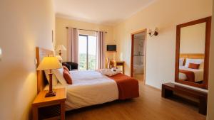 a hotel room with a bed and a mirror at Quinta dos Poetas Nature Hotel & Apartments in Olhão
