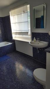 ein Bad mit einem Waschbecken, einem WC und einem Fenster in der Unterkunft Beautiful House in Zehlendorf in Berlin