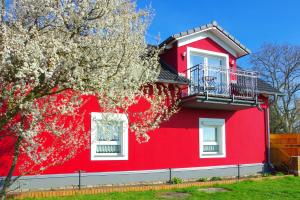 uma casa vermelha com janelas brancas e uma árvore florida em Ferienwohnung Lausitzer Seenland Freienhufen "Annabell" em Grossräschen