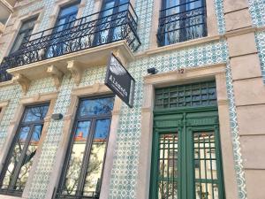 a building with a green door and a sign on it at HOSTEL ALAMEDA EXCLUSIVE HOUSE in Faro