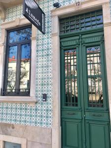 un edificio con puertas verdes y un cartel en él en HOSTEL ALAMEDA EXCLUSIVE HOUSE, en Faro