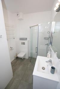 a white bathroom with a shower and a sink at Apartament Sweet Home Pogorzelica in Pogorzelica