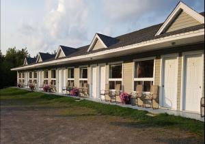 a building with a row of chairs in front of it at Fundy Rocks Motel in Hopewell Cape
