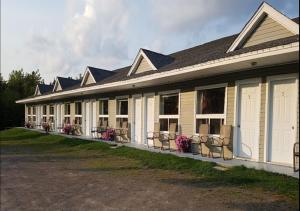 un bâtiment avec une rangée de chaises devant lui dans l'établissement Fundy Rocks Motel, à Hopewell Cape