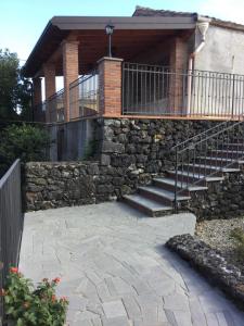 a house with a stone retaining wall and stairs at Villa La Scogliera in Acireale