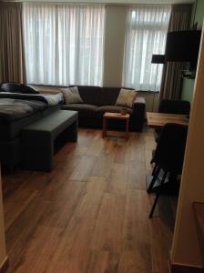 een woonkamer met een bank en een houten vloer bij Studio aan 't Strand Bed by the Sea Adults only in Westkapelle