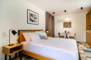 Un dormitorio con una gran cama blanca y una mesa en Biazi Hotel, en Jerusalén