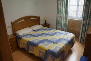 1 dormitorio con 1 cama con edredón azul y amarillo en apartamento do curro, en Muros