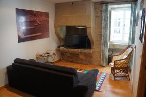 sala de estar con sofá negro y chimenea en apartamento do curro, en Muros