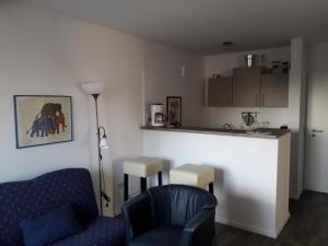 un soggiorno con sedia blu e una cucina di Apartments Norddeicher Straße a Norden