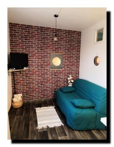 BnBesak Besancon Micropolis في بيزنسون: غرفة معيشة مع أريكة زرقاء أمام جدار من الطوب