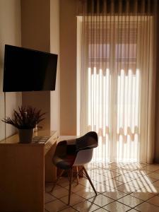 Cette chambre dispose d'une chaise et d'un bureau avec une télévision. dans l'établissement Hotel Residence Risorgimento, à Vibo Valentia