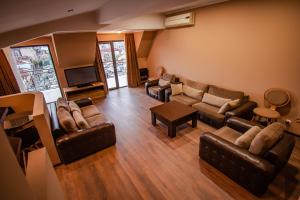 a living room with leather couches and a tv at Daros apartment in Batumi