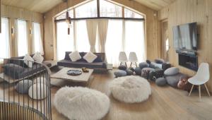 a living room with couches and ottomans at Le Chalet des Boisses, Luxury Ski-In Ski-Out Chalet for 12 in Tignes