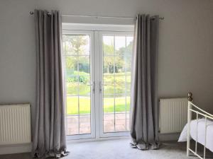 a bedroom with a sliding glass door with curtains at The Old Coach House at Stewton in Louth