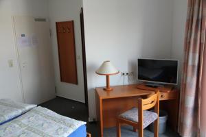 1 dormitorio con escritorio, TV y cama en Wehrstedter Hof en Halberstadt