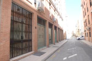 un edificio de ladrillo con puertas de cristal en una calle en habitacion centro historico malaga, en Málaga