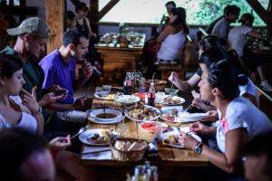 un grupo de personas sentadas alrededor de una mesa comiendo comida en Camp Divlja Rijeka, en Hum