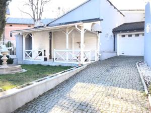 a white house with a garage and a driveway at Pelican Guest House & Hostel in Chernivtsi