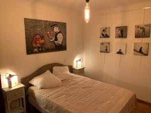 DomazanにあるChez Lydia - Face vignoble, Idéal famille, Billardのベッドと壁に絵が飾られた寝室