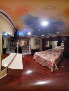 Habitación de hotel con cama y techo con mural en Kearney Motel, en Long Beach