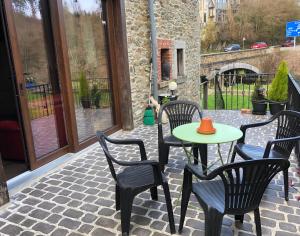a patio with four chairs and a table with an orange hat on it at Au fil de l'eau in Grupont