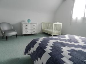 een slaapkamer met een bed, een stoel en een wieg bij La Maison Blanche in Saint-Laurent-sur-Mer