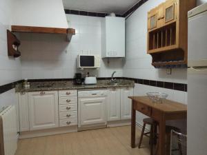 a kitchen with white cabinets and a sink and a table at Casa Rural San Blas in Sanjuanejo