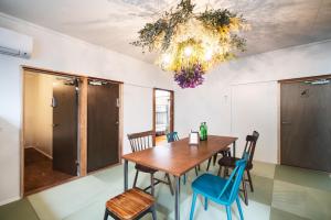Hostel Marika -ホステルマリカ- في نيتشينان: غرفة طعام مع طاولة خشبية وكراسي زرقاء
