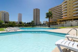 une grande piscine avec deux chaises et certains bâtiments dans l'établissement Praia da Rocha, Algarve Sunny Apartment, à Portimão
