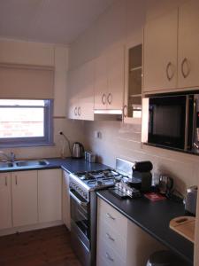 a kitchen with white cabinets and a stove top oven at Acacia Cottage on Peel, Bathurst in Bathurst