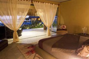 sypialnia z łóżkiem i dużym oknem w obiekcie Samora Luxury Resort w mieście Santa María Colotepec