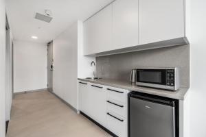 a kitchen with white cabinets and white appliances at Essence Suites Taringa in Brisbane
