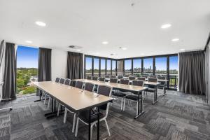 une salle de conférence avec des tables et des chaises et de grandes fenêtres dans l'établissement Essence Suites Taringa, à Brisbane
