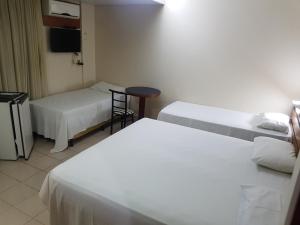 a hotel room with two beds and a television at Oft Plaza Oeste Hotel in Goiânia